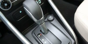 Desligar um carro automático pode parecer uma tarefa simples, mas se não for feito corretamente, pode causar danos significativos à transmissão e resultar em altos custos. Com a crescente popularidade dos carros automáticos no Brasil, é essencial que motoristas compreendam a maneira correta de desligar esses veículos para evitar prejuízos. Cometer erros como engatar a marcha em "P" (Parking) antes de o carro estar completamente parado pode comprometer o funcionamento a longo prazo. Entendendo os Riscos Os problemas ao desligar um carro automático de forma inadequada não se limitam apenas à transmissão. Engates errados podem causar trancos e desgastes prematuros. Em declives, acionar o "P" antes do freio de mão pode sobrecarregar o sistema, levando a avarias. Além disso, motoristas de carros com motor turbo devem esperar alguns segundos antes de desligar o motor para proteger o sistema de lubrificação. Procedimento Correto para Desligar Para garantir a segurança e a longevidade da transmissão, siga o procedimento correto de desligamento: Certifique-se de que o veículo está totalmente parado. Mantenha o pé no freio e mude a alavanca para "N" (Neutro). Acione o freio de mão, garantindo que o peso do carro seja suportado adequadamente. Engate a alavanca em "P". Desligue o motor. Esta sequência não só preserva a transmissão como também aumenta a segurança ao estacionar. Evitando Falhas Futuras Entender os riscos associados ao desligamento inadequado ajuda a evitar falhas no carro. Práticas incorretas podem afetar componentes elétricos e resultar em mensagens de erro no painel. O uso correto da posição "N" e a sequência apropriada são essenciais para evitar trancos em superfícies inclinadas e para preservar o funcionamento do veículo. Benefícios de Pequenos Cuidados Adotar práticas corretas ao desligar um carro automático é mais do que uma questão de evitar reparos dispendiosos. É um investimento na longevidade e eficiência do veículo. Com motoristas cada vez mais optando por modelos automáticos, o conhecimento das melhores práticas de desligamento se torna indispensável. Informações adequadas e a implementação desses cuidados no dia a dia podem prevenir muitos problemas futuros e garantir que seu carro esteja sempre em ótimas condições de uso. Em outubro de 2023, o aumento da frota de veículos automáticos no Brasil destaca a importância de seguir esses passos corretos de desligamento. Proteger seu investimento e garantir uma condução mais tranquila são razões suficientes para adotar essas práticas.