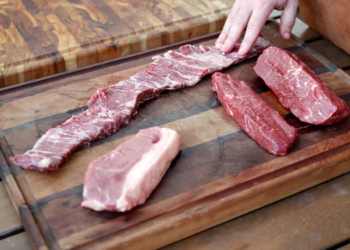 Lugar da sua cozinha está infestado de bactérias e você coloca comida nele todo dia Seja de madeira, bambu, vidro, plástico ou inox, cada tipo de tábua requer cuidados específicos para manter a higiene adequada. A higienização correta das tábuas de cozinha é fundamental tanto em cozinhas domésticas quanto em profissionais, onde a contaminação cruzada pode ocorrer. Garantir a segurança alimentar é a principal razão para seguir métodos adequados de desinfecção, além de contribuir para a longevidade do utensílio. A importância da limpeza correta das tábuas Entender a importância da limpeza regular é o primeiro passo para garantir que sua tábua de cozinha permaneça livre de contaminação. Durante o uso diário, a tábua de corte acumula resíduos de diversos alimentos, tornando-se um potencial vetor para bactérias perigosas. Dessa forma, a higienização não só previne contaminação, mas também aumenta a durabilidade dos materiais de que é feita. Métodos de desinfecção para tábuas de madeira e bambu Tábuas de madeira e bambu são populares, mas exigem cuidados específicos devido à sua porosidade. Recomenda-se lavar com detergente neutro e água corrente usando uma esponja macia. Após a lavagem, é crucial permitir que sequem completamente em um local ventilado, longe da luz solar direta para evitar rachaduras. Para uma desinfecção mais profunda, misture uma solução de uma colher de sopa de água sanitária para cada galão de água, aplicando na tábua com um pano e deixando agir por apenas 2 minutos antes de enxaguar. Higienizando tábuas de plástico e vidro As tábuas de plástico podem ser lavadas na lava-louças, mas é recomendável deixá-las de molho em uma solução de água sanitária antes, para garantir que as ranhuras também sejam limpas. Uma solução eficaz para manchas e odores é a combinação de bicarbonato de sódio e limão: polvilhe bicarbonato na superfície, esfregue com meio limão, deixe agir e enxágue bem. Já as tábuas de vidro necessitam apenas de uma lavagem com detergente comum e água, sendo fáceis de higienizar, porém cuidar do fio das facas é essencial devido à superfície dura do vidro. Cuidados específicos com tábuas de inox As tábuas de inox, usadas eventualmente em cozinhas, não devem ser expostas à água sanitária, pois isso pode provocar corrosão. O melhor método é usar água e detergente, sempre enxaguando completamente. Mantenha-as longe de substâncias abrasivas que possam comprometer sua superfície. Independentemente do tipo de tábua, práticas gerais de manutenção incluem raspar os resíduos logo após o uso e armazenar em locais secos e arejados. Isso impede que bactérias e fungos se desenvolvam. Escolhendo a tábua ideal para sua cozinha A escolha da tábua ideal deve considerar o uso pretendido e a facilidade de limpeza dos materiais. Conhecendo as propriedades específicas de cada material, você pode decidir qual atende melhor seus requisitos sem comprometer a segurança dos alimentos preparados. Aplicando essas práticas, não apenas protege-se a sua cozinha, mas também se preserva a saúde daqueles que compartilham as refeições. Uma boa rotina de limpeza não apenas minimiza riscos, como também garante a longa vida útil das tábuas de corte. A correta desinfecção e manutenção preventiva são passos essenciais para manter o ambiente da sua cozinha mais higiênico e seguro.