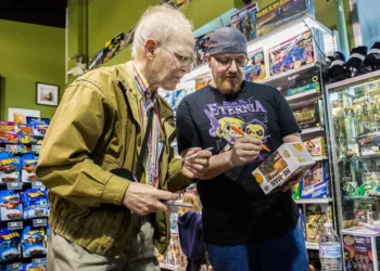 Sweet (à esquerda) assinando um Funko Pop do He-Man.

Reprodução: Olivia Vanni / The Herald